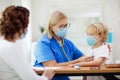 Doctor examining sick child in face mask