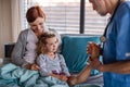 Doctor examining a small hospitalized girl with mother in hospital.