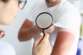 Doctor examining sunburns on patient arm using magnifying glass closeup Royalty Free Stock Photo