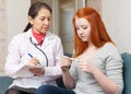 Doctor examining teenager patient with thermometer