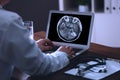 Doctor examining x-ray of patient with brain cancer on laptop in clinic Royalty Free Stock Photo