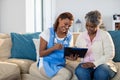 Doctor explaining medication on clipboard to senior woman in living room Royalty Free Stock Photo