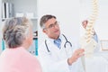 Doctor explaning anatomical spine to senior woman