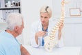 Doctor explaning spine model to senior patient