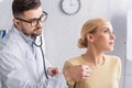 doctor in eyeglasses examining blonde woman