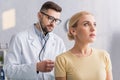 doctor in eyeglasses examining blonde woman