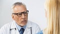 doctor in eyeglasses listening to woman