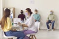 Doctor in face mask interviewing young woman before giving her antiviral vaccine Royalty Free Stock Photo