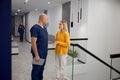 Doctor and female patient discussing something while standing in clinic corridor Royalty Free Stock Photo