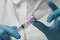 Doctor filling syringe with hepatitis vaccine from glass vial, closeup