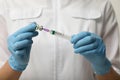 Doctor filling syringe with hepatitis vaccine from glass vial, closeup