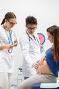 The attending physician checks with his hand how the baby in the pregnant patient's abdomen is moving. A professional Royalty Free Stock Photo