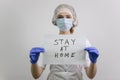 Doctor girl holding a `stay home` sign. Encourages people to fight the coronavirus without violating the quarantine. Covid-19 viru