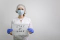 Doctor girl holding a `stay home` sign. Encourages people to fight the coronavirus without violating the quarantine. Covid-19 viru