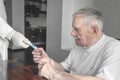 Doctor gives a thermometer to measure the temperature of an older sick patient. A gray-haired old man takes the thermometer from