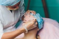 Doctor giving face lifting injection on mid age woman in the forehead between eyebrows to remove expression wrinkles in Royalty Free Stock Photo