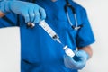 Doctor with gloves filling a syringe with liquid