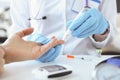 Doctor with gloves piercing patients finger with lancet closeup