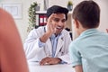 Doctor Or GP In White Coat Meeting Mother And Son For Appointment Giving Boy High Five