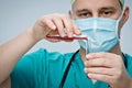 The doctor in a green hat and mask pours red liquid from one test tube to another. Royalty Free Stock Photo