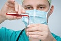 The doctor in a green hat and mask pours red liquid from one test tube to another. Royalty Free Stock Photo