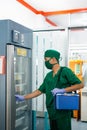 doctor carries a blood bag box while opening storage cabinet