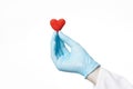 Doctor hand in blue glove holding a crochet red heart on a white background. Cardio care and love medical concept Royalty Free Stock Photo