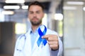 Doctor hand with blue prostate cancer awareness ribbon. Medicine oncology closeup sky symbol