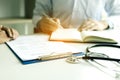 Doctor hand holding pen writing patient history list on note pad and talking to the patient about medication and treatment Royalty Free Stock Photo