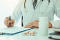 Doctor hand holding pen writing patient history list on note pad and talking to the patient about medication and treatment Royalty Free Stock Photo