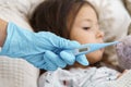 Doctor hand in medical glove hold thermometer for measuring temperature of sick child. Selective focus, closeup view. Royalty Free Stock Photo