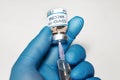 Coronavirus conceptual image of doctor hand in surgical glove holding a vaccine bottle with injection syringe in close up view Royalty Free Stock Photo