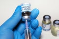 Coronavirus conceptual image of doctor hand in surgical glove holding a vaccine bottle with injection syringe in close up view Royalty Free Stock Photo