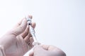 Doctor hand wears white medical glove holding flu, covid-19 liquid vaccine vial bottle and syringe are filling for injection Royalty Free Stock Photo