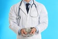 Doctor in handcuffs with bribe on light blue background. Corrupted medicine Royalty Free Stock Photo