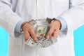 Doctor in handcuffs with bribe on light blue background, closeup. Corrupted medicine Royalty Free Stock Photo