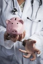 Doctor In Handcuffs Holding Piggy Bank Wearing Lab Coat, Stethoscope Royalty Free Stock Photo