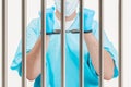 Doctor in handcuffs is standing behind a prison cell. The concept of corruption in medicine