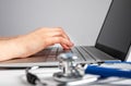 Doctor hands closeup typing on laptop keyboard. Woman sitting at office desk with computer and stethoscope and taking Royalty Free Stock Photo