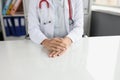 Doctor hands are folded on desktop in clinic