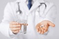 Doctor hands giving white pills and glass of water Royalty Free Stock Photo