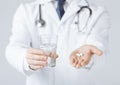 Doctor hands giving white pills and glass of water Royalty Free Stock Photo