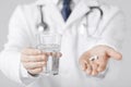 Doctor hands giving white pills and glass of water Royalty Free Stock Photo