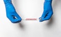 Doctor hands in gloves holding test tube for 2019-nCoV coronavirus. Covid tube over white background, top view