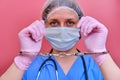 Doctor hands in handcuffs on pink background, close up. Young woman hands in medical gloves handcuffed, coronavirus quarantine