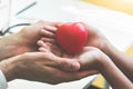 Doctor hands holding and giving red massage heart to patient lit