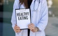 Doctor hands holding white card sign with Healthy Eating text message Royalty Free Stock Photo