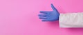 Doctor hands wear purple latex glove on pink background.He wear long sleeve gown.Empty hand