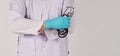 The doctor has embraced and hands with a stethoscope. Hand wears the blue medical glove and a long-sleeve gown on white background Royalty Free Stock Photo