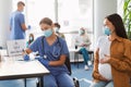 Doctor having Appointment For Vaccination To Smiling Pregnant Lady